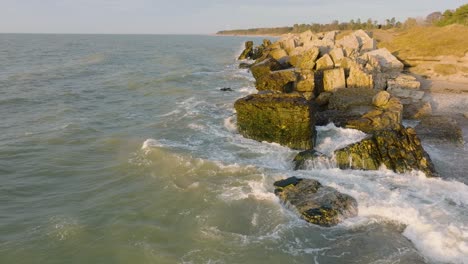 beautiful aerial establishing view of karosta concrete coast fortification ruins, vibrant sunset over stormy baltic sea, winter evening, slow motion drone shot moving forward