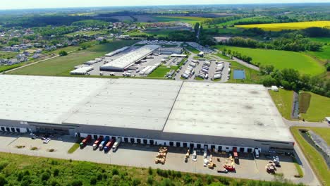 buildings of logistics center, warehouses near the highway, truck parking process, view from height, a large number of trucks in the parking lot near warehouse