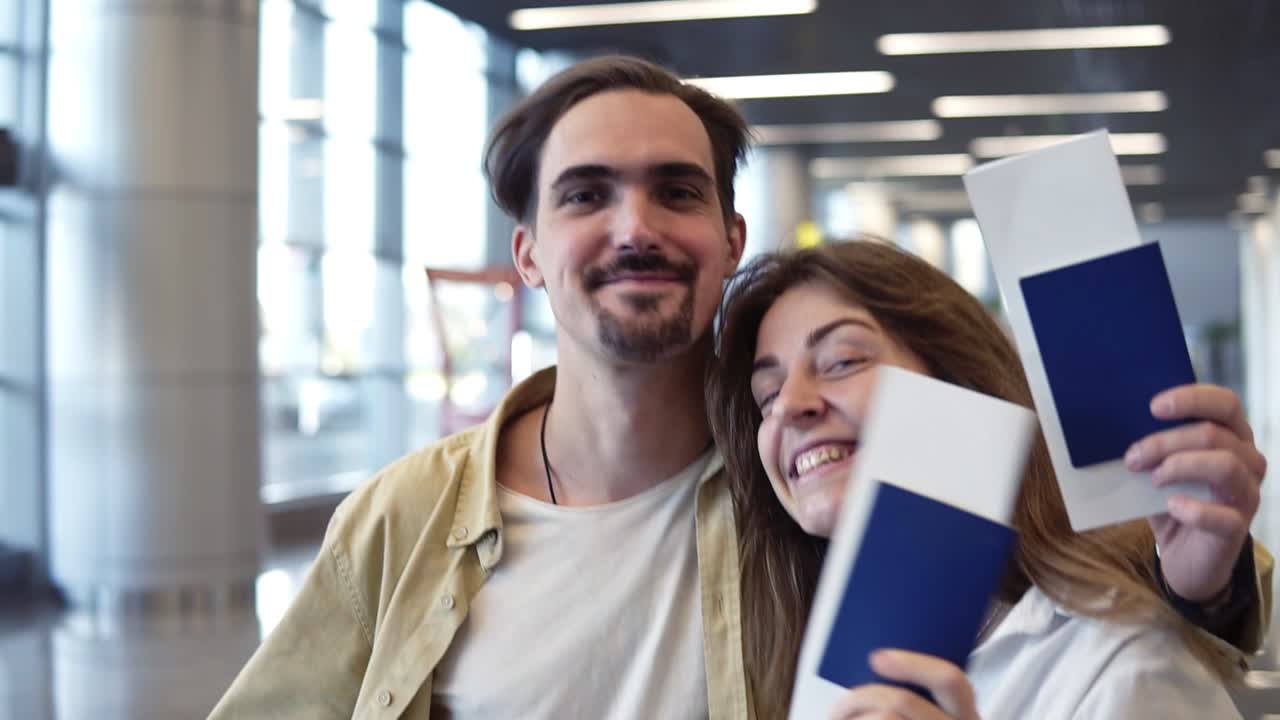retrato de una pareja caucásica emocionada que va de vacaciones. caminando por el aeropuerto y sosteniendo pasaportes, tarjetas de embarque.
