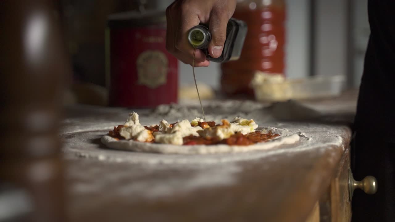 Olivenöl auf roher hausgemachter Käsepizza auf Holztisch in Zeitlupe 60FPS