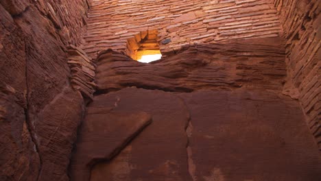 a moving tilt-up shot revealing a stone wall and window of the largest pueblo at wupatki national monument in arizona