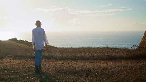 blonde tourist walking ocean at meadow. traveling woman enjoying sea vacation