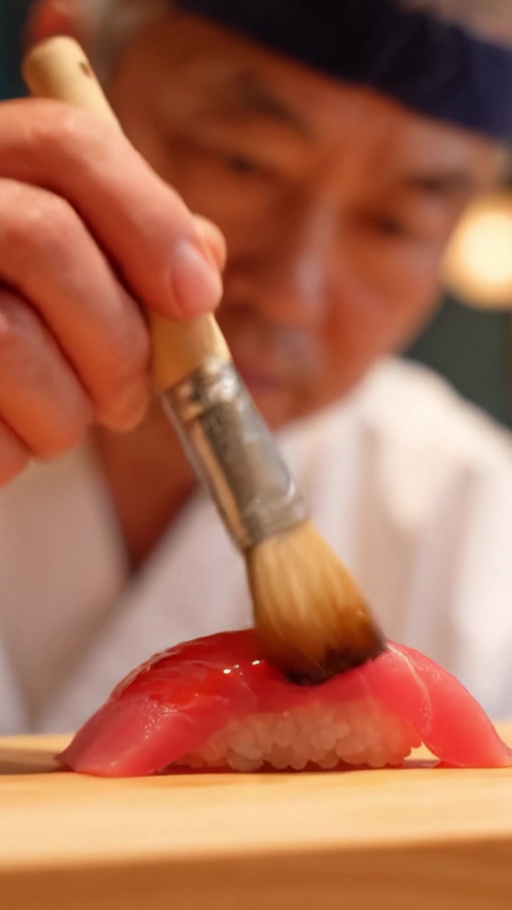 Um Mestre Sushiman observa atentamente uma peça de sushi perfeitamente elaborada, exibindo a arte e a precisão da maestria culinária na culinária japonesa.
