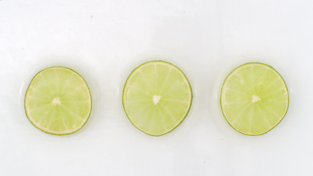 물 속의  바탕에 놓인 초록색 라임의 세 조각에 천천히 물이 어집니다.