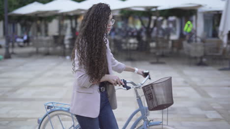young woman with curly hair on bicycle in city