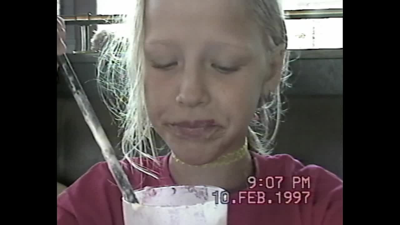 A young girl eating a milkshake