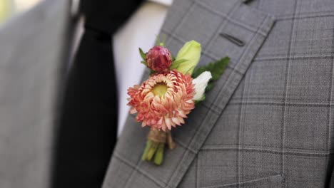 young man or groom in formal suit with pink and green flower boutonniere and black tie 1080p 60fps