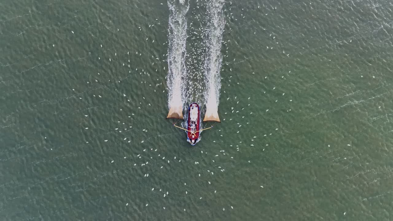 드론 은 물 을 통해 그물 을 끌고 가는 어부 의 배 를 위 에서 아래 로 다