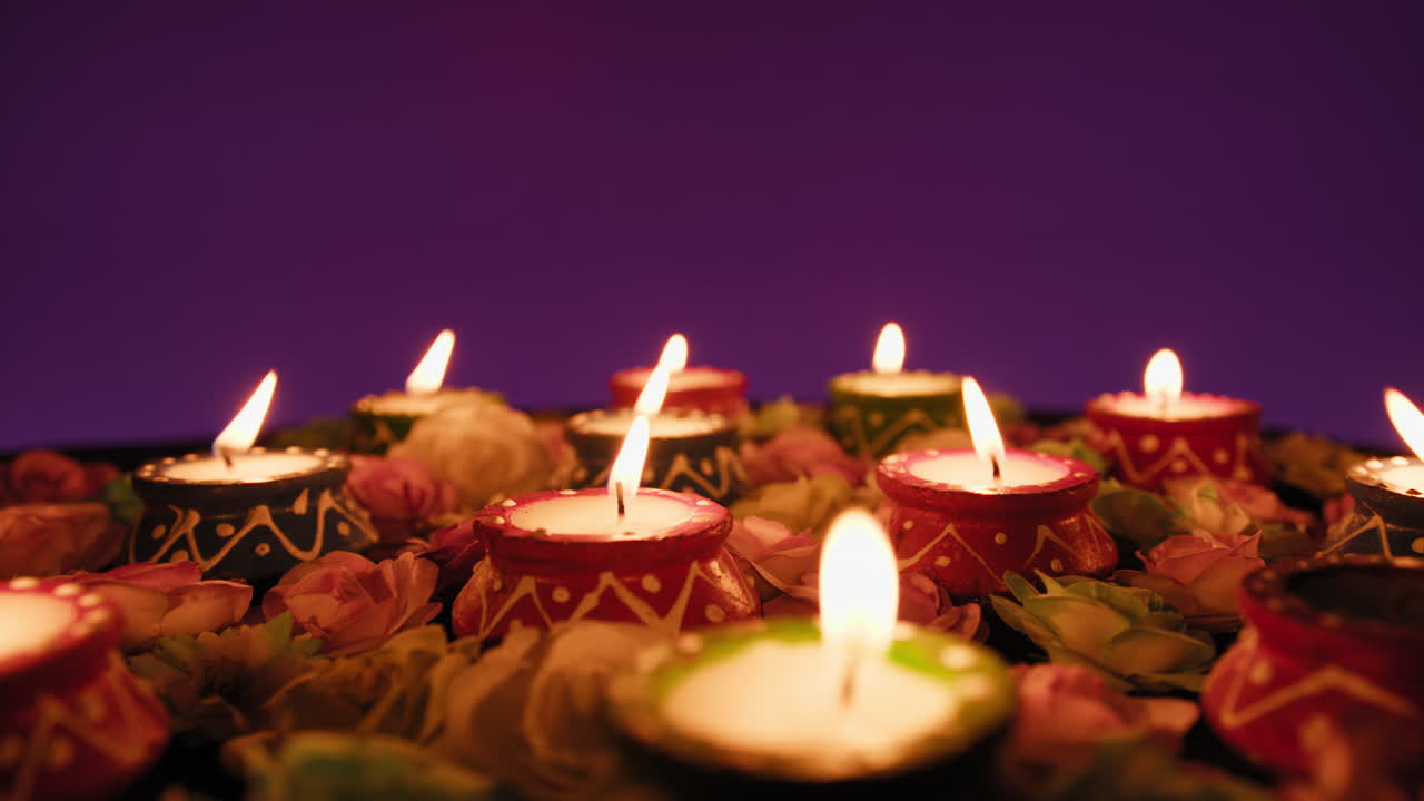 Ruce zapalují malé svíčky pro indickou oslavu Diwali