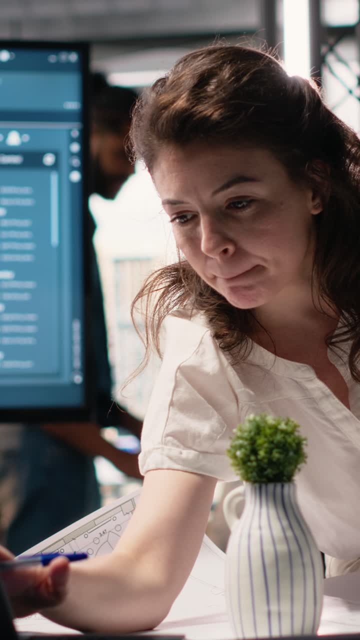 Vertical Video Woman real estate engineer reviews city planning blueprints on laptop