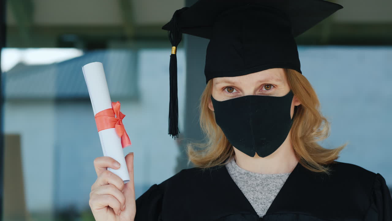 una graduada con una máscara tiene un diploma en la mano