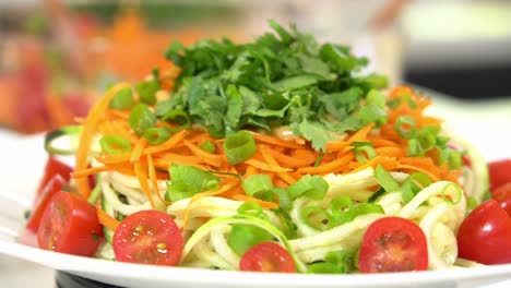 plato giratorio de fideos de calabacín tomates en rodajas espiralizador para hacer fideos de calabacín zoodles añadiendo al cuenco saludable vegano vegetariano estilo de vida dieta de desintoxicación