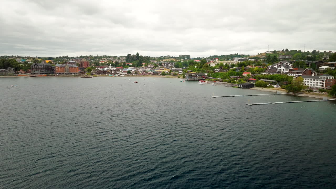 Aerial pullback along Lake Llanquihue and surrounding hills near Puerto Varas, southern Chile, coastal buildings and boats