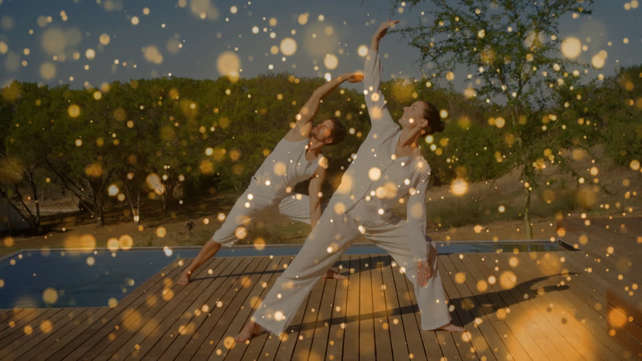 Animation of floating light spots over caucasian couple practicing yoga