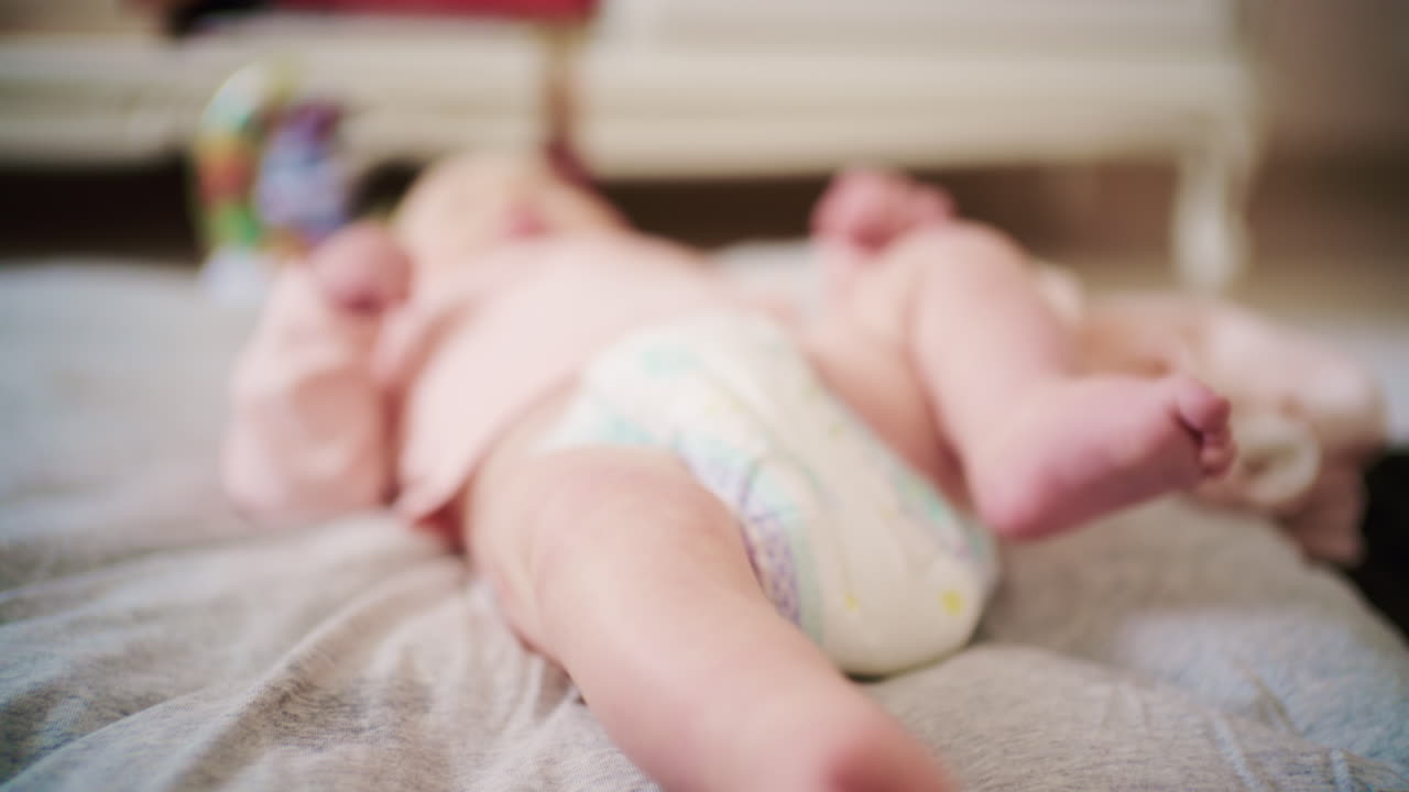 Close up of a newborn baby's feet gently moving while lying on a soft bed