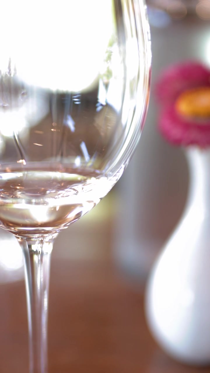 Nærbillede af et hvidvinsglas på et bord med blød bokeh-belysning