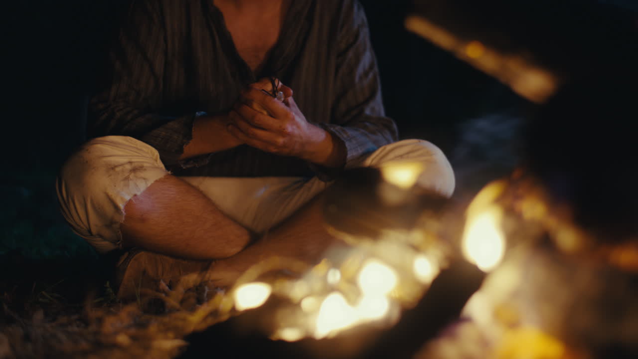 Person sitting by a campfire at night