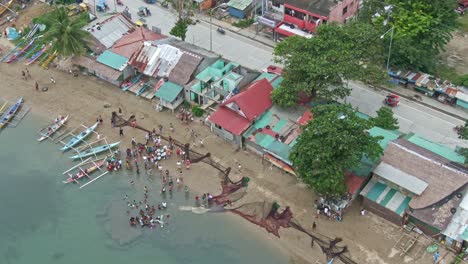 top down shot of group of people at seaside, fishermen washing the fishing net at shallow part of the seashore