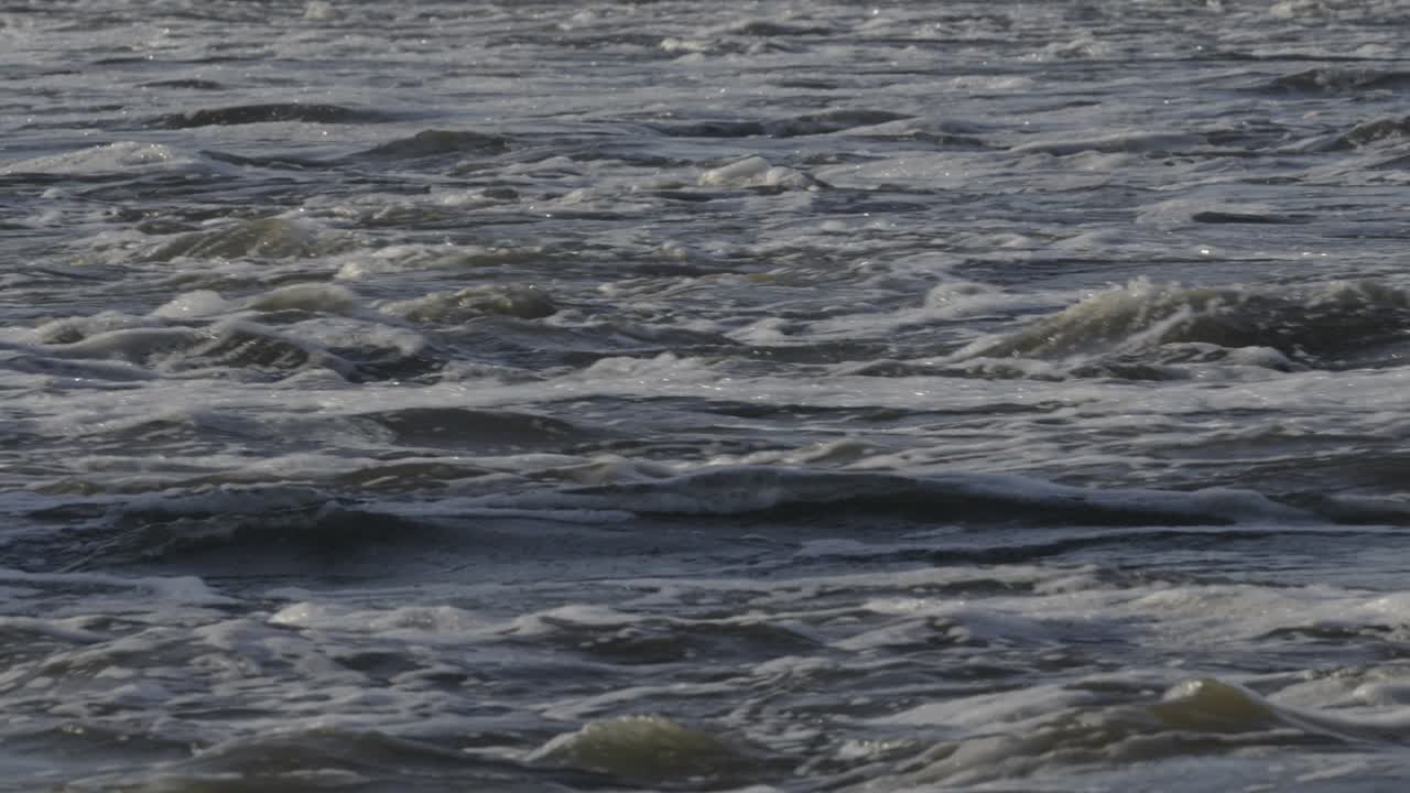 Close-up of choppy water with waves and ripples, fast movement and texture of river stream. Slow motion