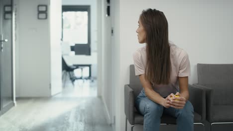 Wide-shot-of-stressed-caucasian-woman-sitting-in-clinic-waiting-room-and-squeezing-a-stress-ball