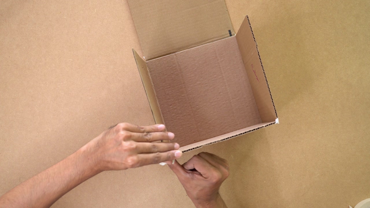 Person taping cardboard box edges, diy paper crafts