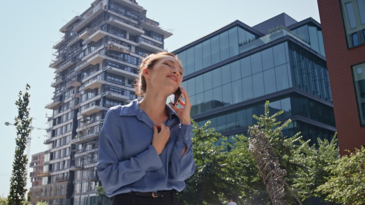 mujer alegre hablando por teléfono móvil caminando por la ciudad soleada de cerca. chica hablando por teléfono