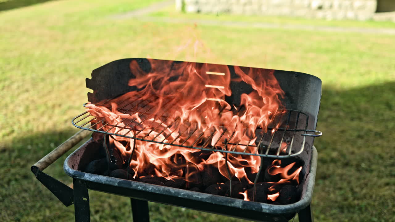 屋外バーベキューグリルに燃える熱い熾火。肉を焼くために火花を散らす明るい焚き火。グリルの中の炎。