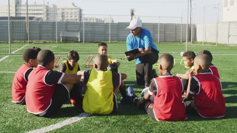 Soccer-kids-in-cercle-and-listening-to-the-coach-in-a-sunny-day