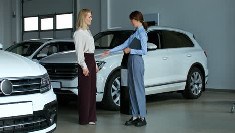 businesswomen discussing car purchase in showroom