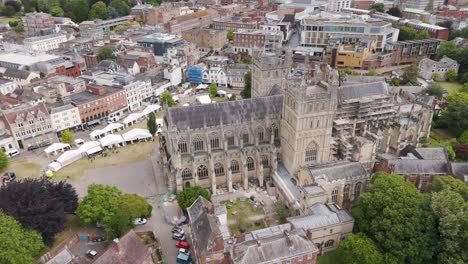 Drone-orbital-view-showcasing-the-intricate-architecture-of-Exeter-Cathedral-surrounded-by-lush-greenery,-Exeter,-Devon,-UK