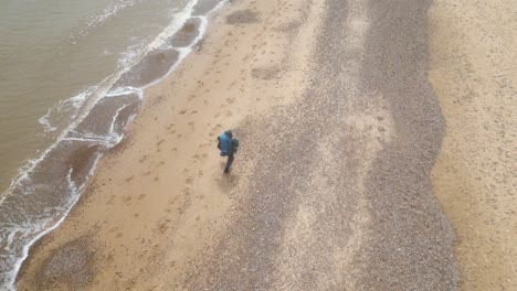 Vista-Aérea-De-Un-Turista-Con-Mochila-Caminando-Por-La-Playa-De-Kessingland-En-Suffolk,-Inglaterra.