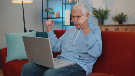 Happy-senior-old-man-working-on-laptop-celebrate-success-win-money-in-lottery-get-online-good-news