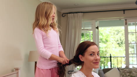 little girl plaiting her mothers hair in the morning