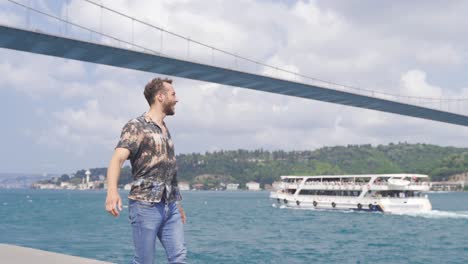 A-very-happy-young-man-is-walking-against-the-view-of-the-Bosphorus.