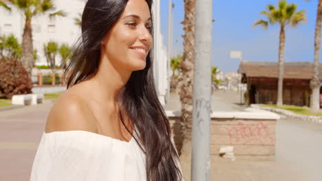 brunette woman sitting on beach promenade wall