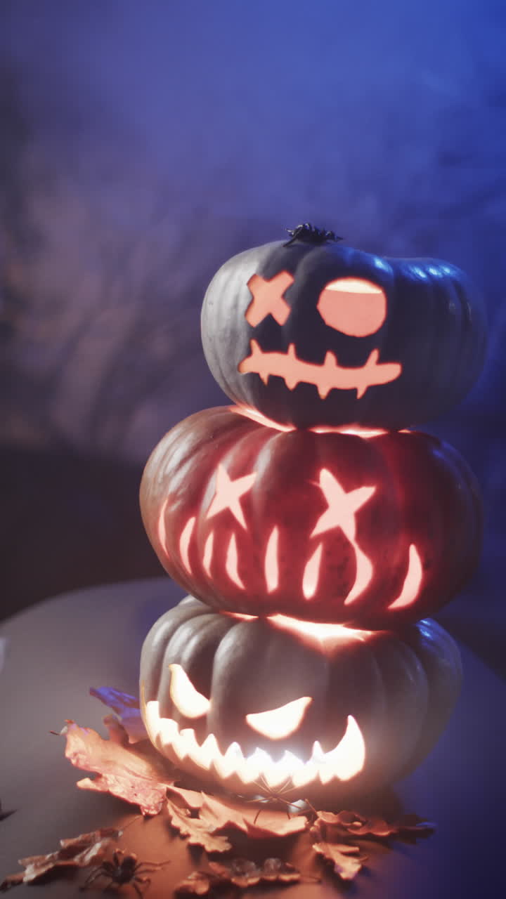Vertical video of halloween carved pumpkins and smoke with copy space on blue background