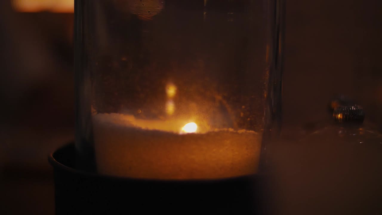 Close Up of candle burning in glass vase, the wax is low from extended usage