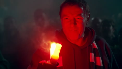 man holding a red flare in a crowd at night