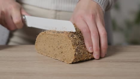 primer plano, manos tratando pero fallando en cortar pan integral