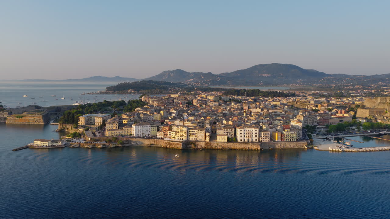 Swallows fly in air, sunrise light above rooftops of Old Town Corfu, Greece, drone dolly approach