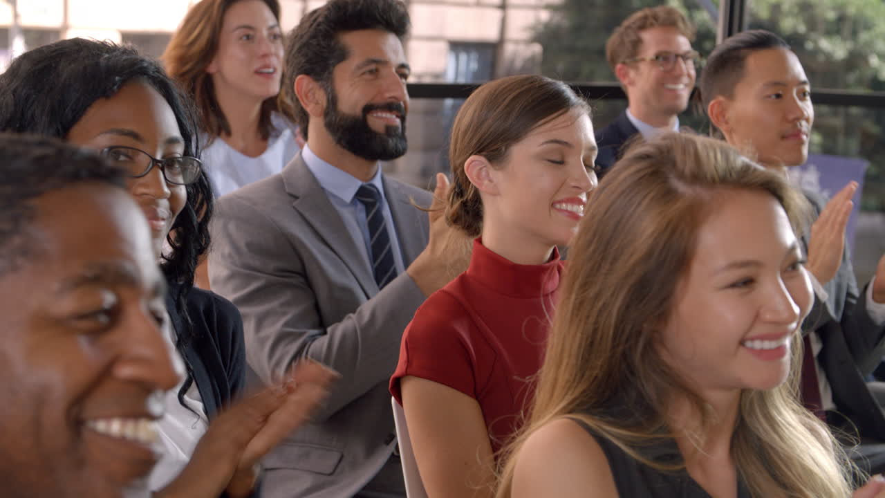 Pubblico che applaude a un seminario aziendale, primo piano.