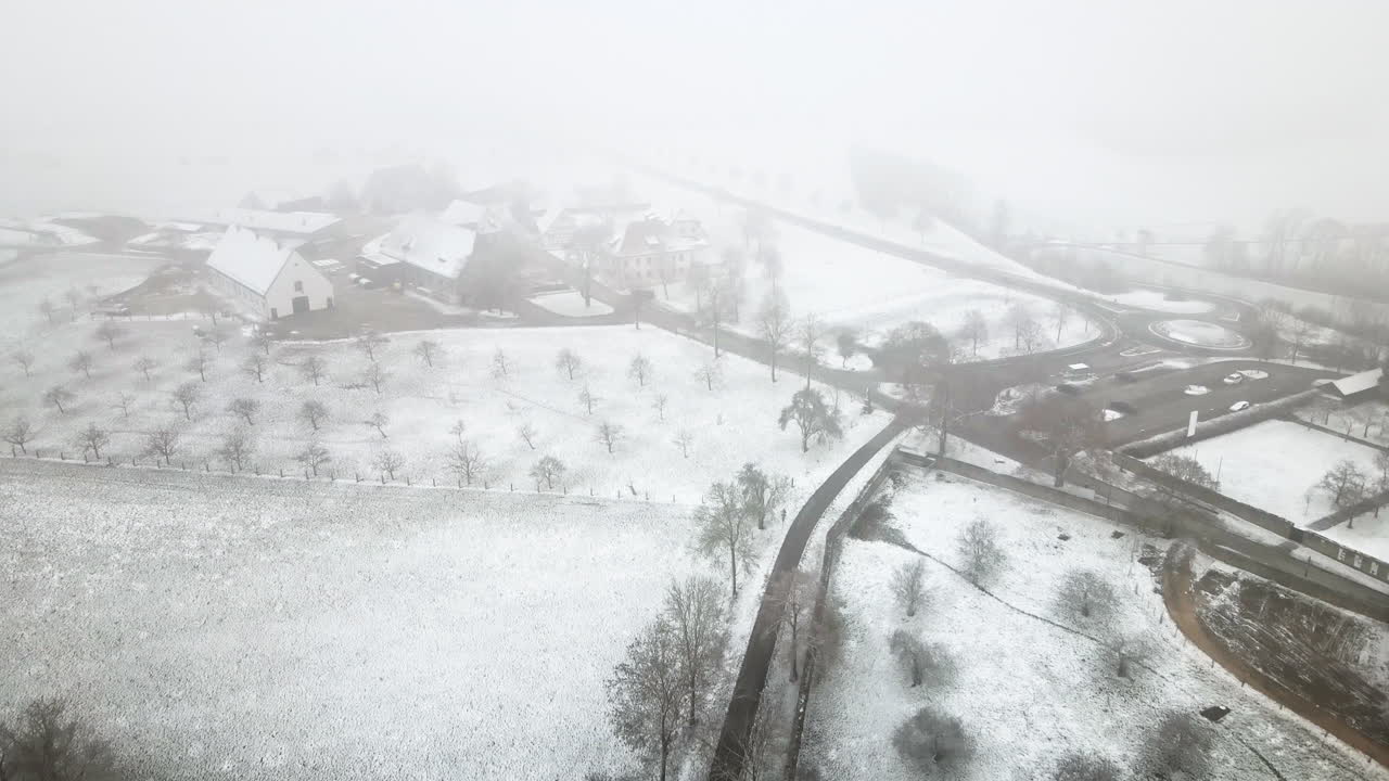 4K luftdrone flyver fremad over et snedækket tysk landskab. Premium vinter stockoptagelser til rejser, dokumentarfilm og virksomhedsindhold. Afslører landligt landskab, veje og landbrugsmarker.