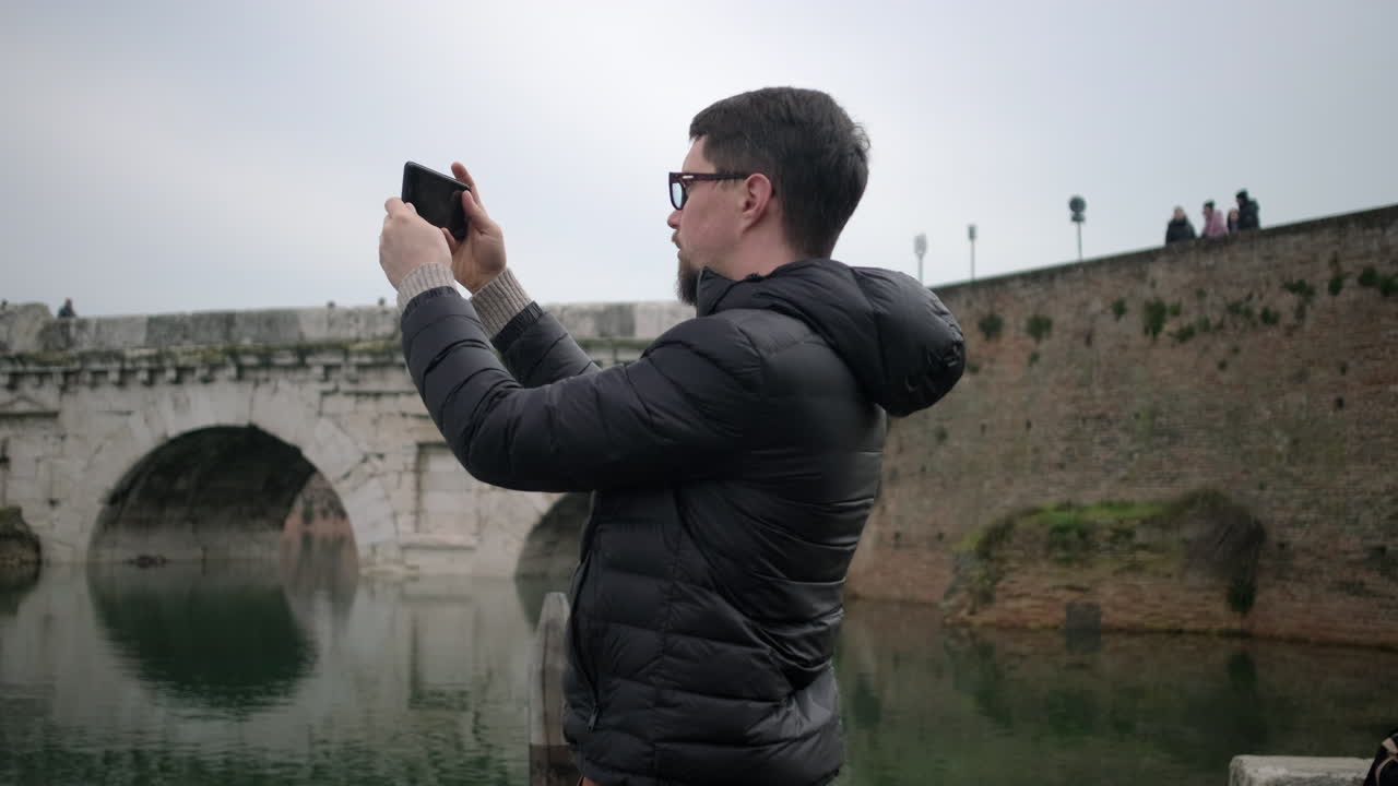Man taking photo of a historic bridge