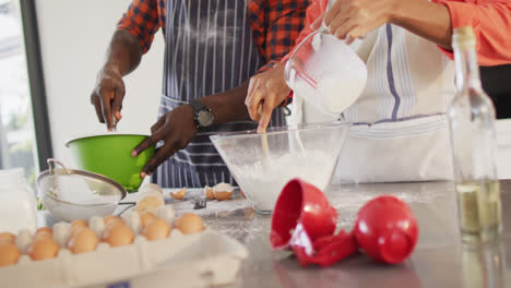 Video-of-midsection-of-african-american-couple-baking-together-in-kitchen