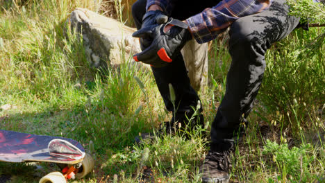 side view of cool young caucasian man with skateboard relaxing at countryside in the sunshine 4k