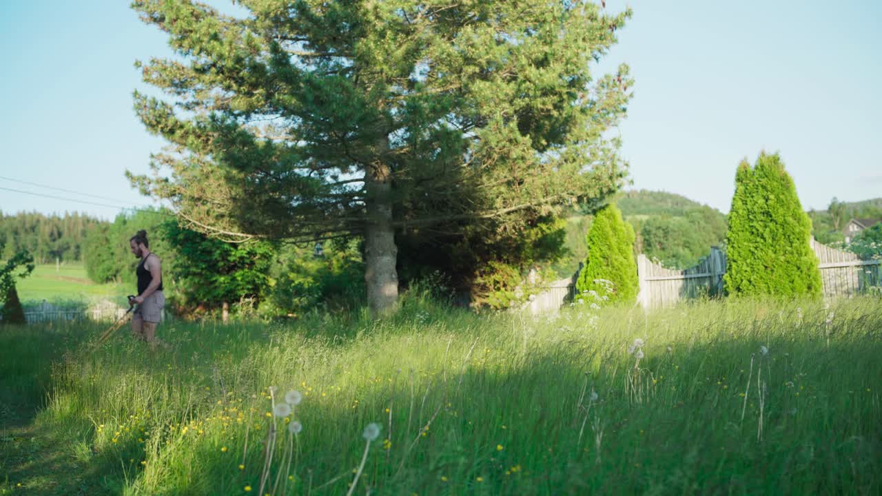 A Man Pushing Lawnmower Cutting Overgrown Grass At The Yard