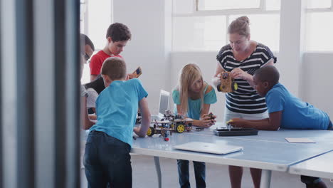 students with teachers in after school computer coding class learning to program robot vehicle