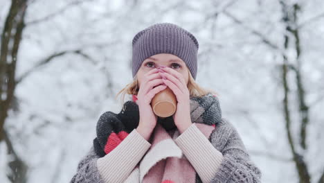 a woman warms up with a hot ay in a winter park