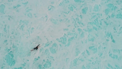 Drone-top-down-overview-of-surfers-paddling-through-whitewash,-Cloudbreak-Fiji