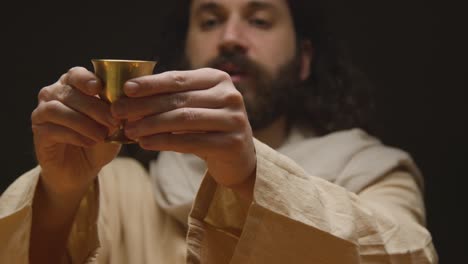 Studio-Shot-Of-Man-Wearing-Robes-With-Long-Hair-And-Beard-Representing-Figure-Of-Jesus-Christ-Blessing-Chalice-Of-Wine-1